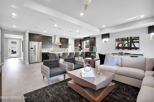 living room with a tray ceiling, ceiling fan, and sink