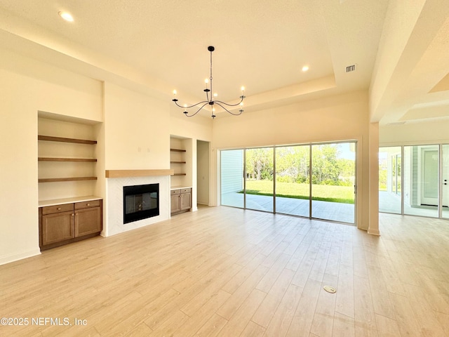 269 Pasarela Dr, Saint Augustine, FL 32095 - unfurnished living room with a notable chandelier, a glass covered fireplace, plenty of natural light, built in shelves, and visible vents