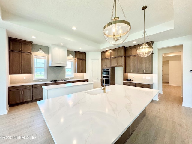269 Pasarela Dr, Saint Augustine, FL 32095 - kitchen with gas cooktop, a sink, a large island, light wood-type flooring, and a tray ceiling