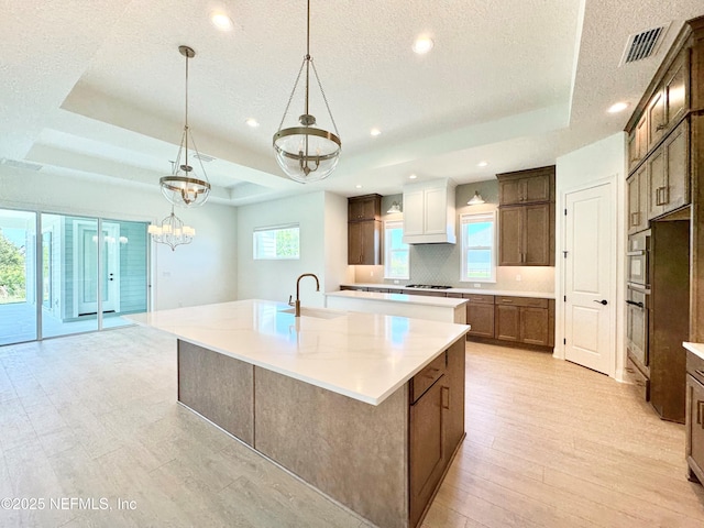 269 Pasarela Dr, Saint Augustine, FL 32095 - kitchen featuring a sink, a large island with sink, tasteful backsplash, a tray ceiling, and visible vents