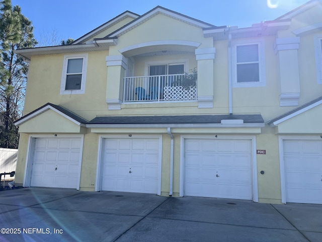 view of property with a garage, a balcony, and stucco siding