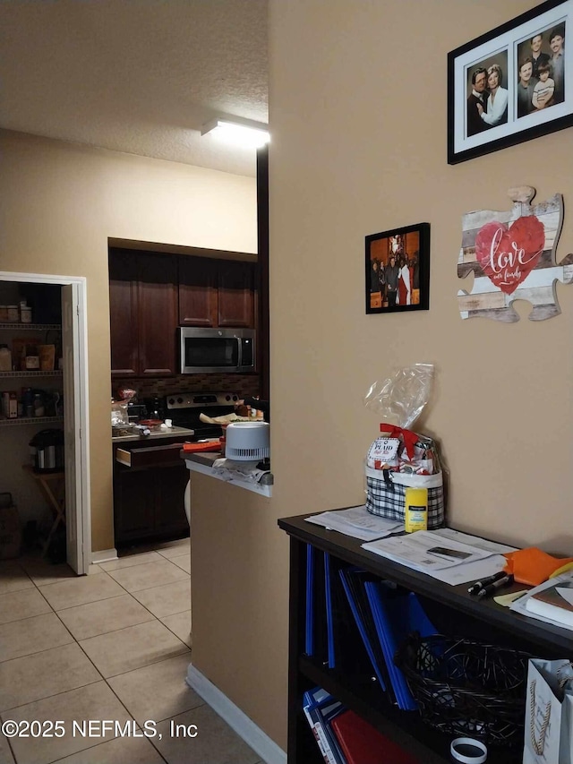 kitchen with electric range, dark brown cabinets, light tile patterned flooring, and a textured ceiling