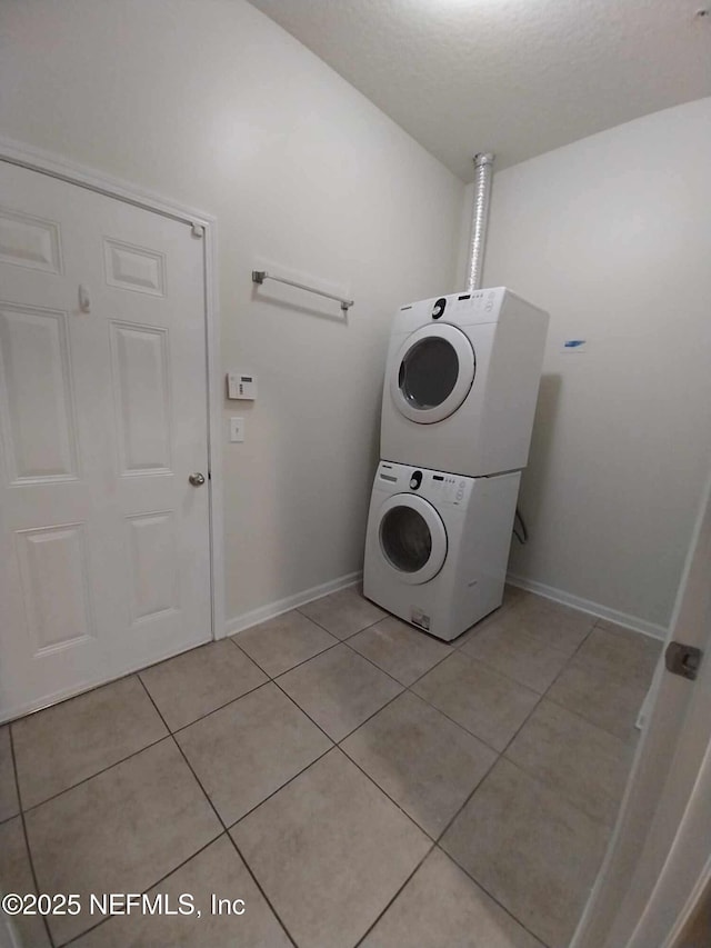 laundry room featuring stacked washer and clothes dryer and light tile patterned flooring