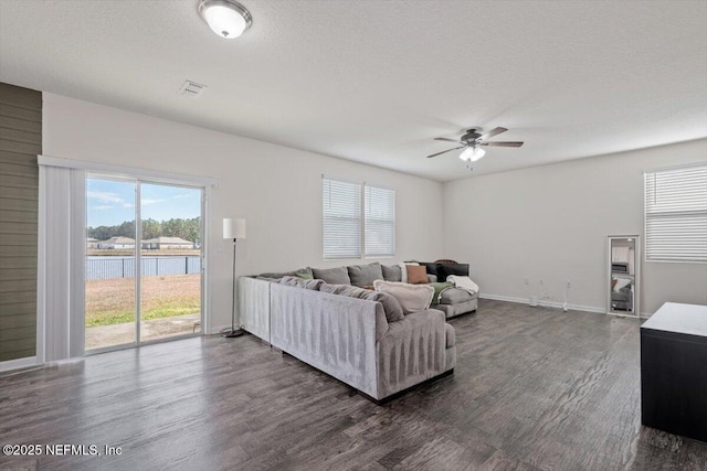 living room with ceiling fan, dark hardwood / wood-style floors, a water view, and a textured ceiling