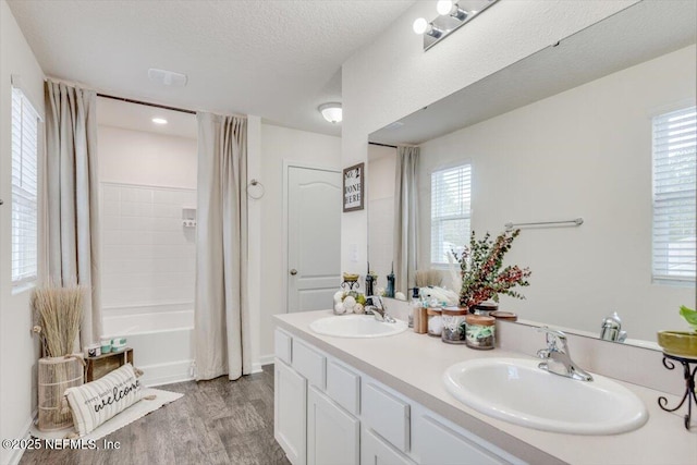 bathroom featuring a healthy amount of sunlight, a textured ceiling, vanity, shower / tub combo, and hardwood / wood-style flooring