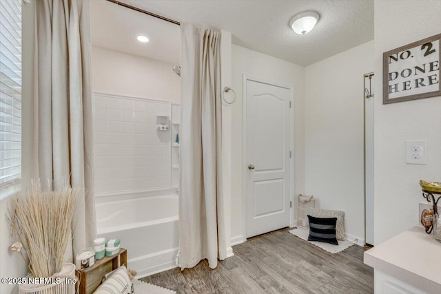 bathroom featuring shower / bath combination with curtain, wood-type flooring, and a textured ceiling