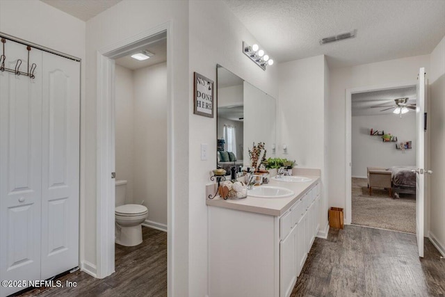 bathroom featuring ceiling fan, hardwood / wood-style floors, a textured ceiling, toilet, and vanity