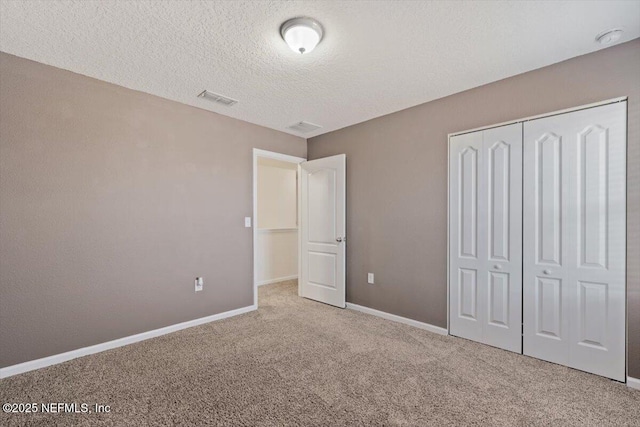 unfurnished bedroom with carpet floors, a textured ceiling, and a closet