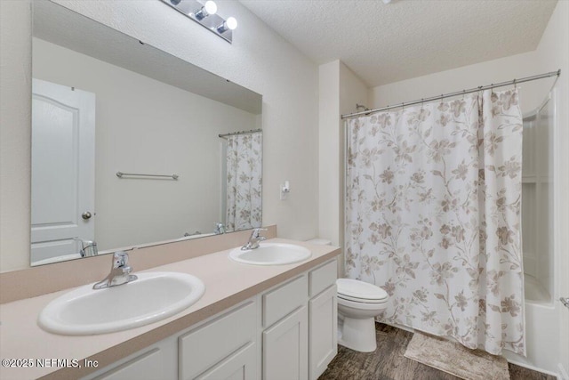 full bathroom featuring shower / tub combo, vanity, a textured ceiling, hardwood / wood-style flooring, and toilet