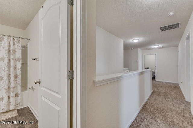 corridor featuring light carpet and a textured ceiling