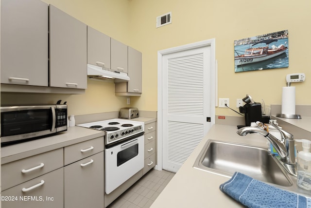 kitchen featuring light tile patterned floors, white range oven, gray cabinets, and sink