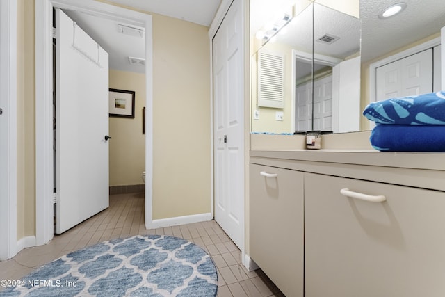 bathroom with tile patterned floors, vanity, a textured ceiling, and toilet