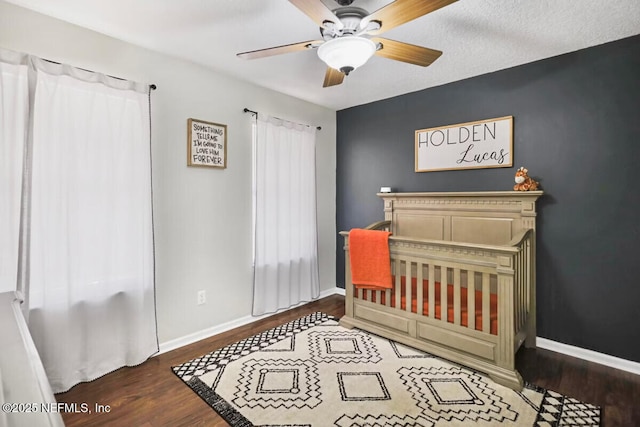 bedroom with multiple windows, ceiling fan, dark hardwood / wood-style flooring, and a crib