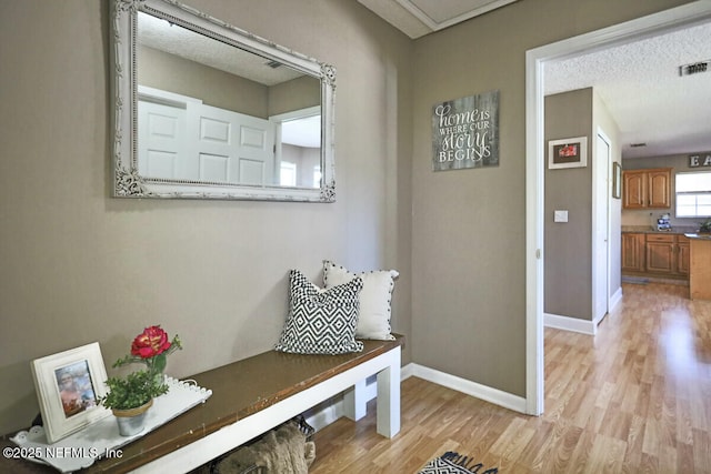 mudroom with light wood-type flooring and a textured ceiling