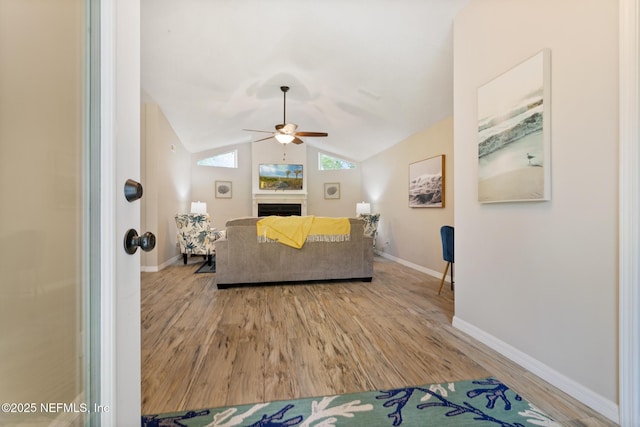 living room featuring ceiling fan, light wood-type flooring, and vaulted ceiling