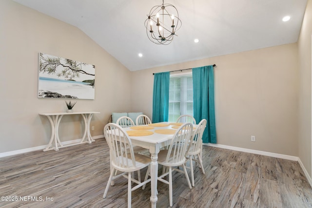 dining area featuring hardwood / wood-style floors, lofted ceiling, and a chandelier