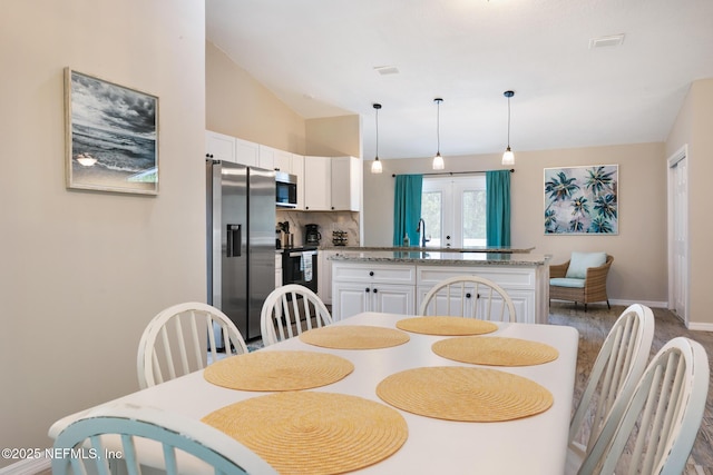 dining space featuring lofted ceiling, sink, and french doors