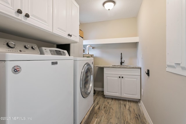 washroom featuring sink, cabinets, washing machine and dryer, a textured ceiling, and hardwood / wood-style flooring