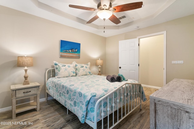 bedroom featuring ceiling fan, a raised ceiling, and dark wood-type flooring