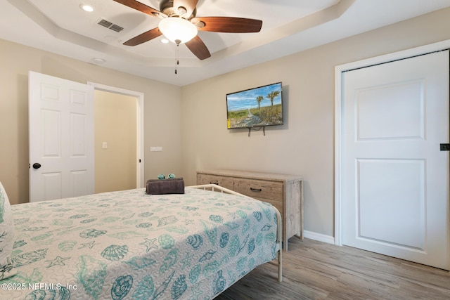 bedroom featuring a tray ceiling, ceiling fan, and hardwood / wood-style flooring