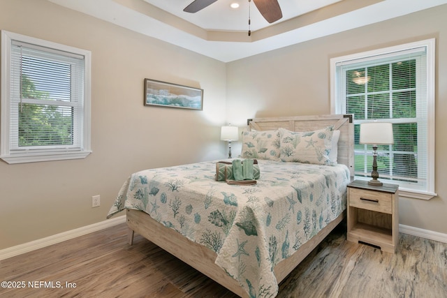 bedroom featuring a tray ceiling, ceiling fan, and hardwood / wood-style floors