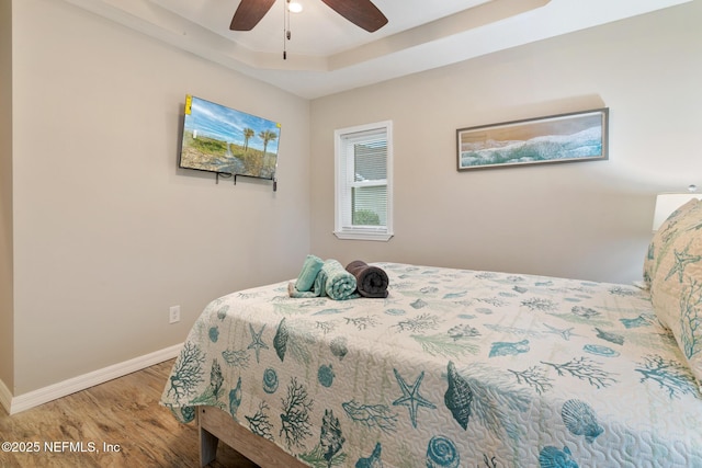 bedroom with a raised ceiling, ceiling fan, and hardwood / wood-style floors