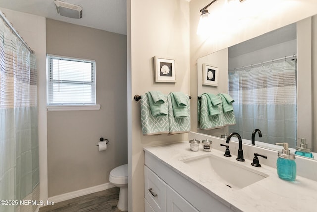 bathroom with hardwood / wood-style floors, vanity, toilet, and walk in shower