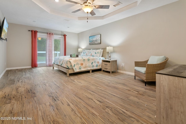 bedroom with ceiling fan, a raised ceiling, light wood-type flooring, and access to outside