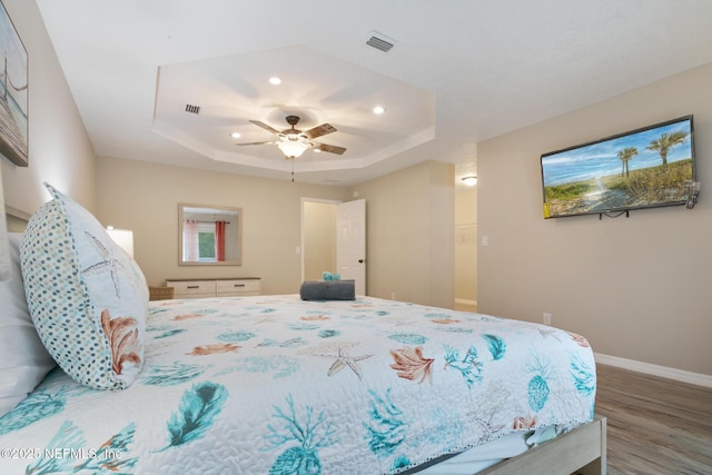 bedroom featuring wood-type flooring, a tray ceiling, and ceiling fan