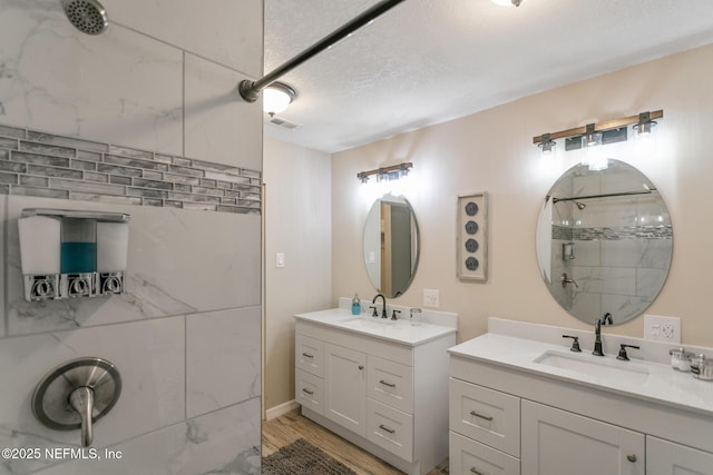 bathroom featuring tiled shower, a textured ceiling, vanity, and hardwood / wood-style flooring