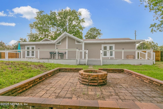 rear view of property with a fire pit, a deck, and a patio