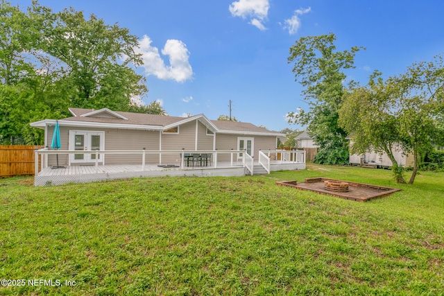 rear view of property with a lawn, a deck, an outdoor fire pit, and french doors