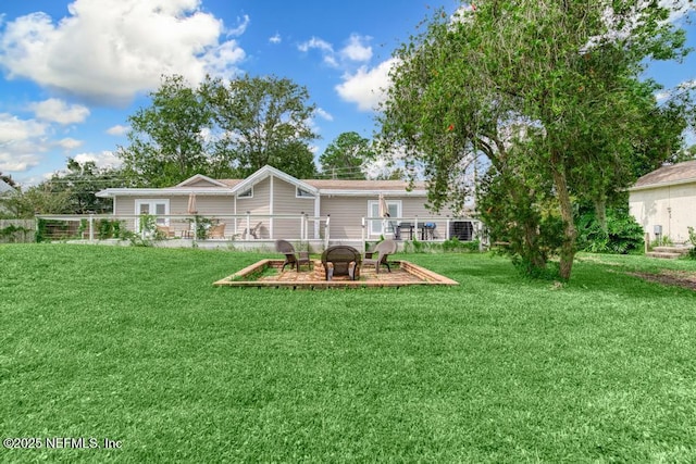 back of house with a yard and an outdoor fire pit