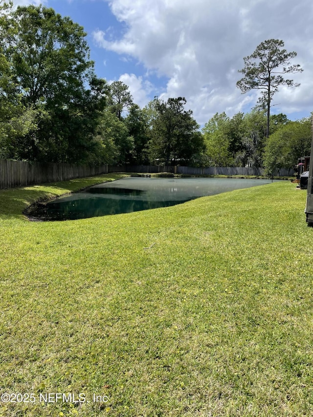 view of yard with a water view and fence