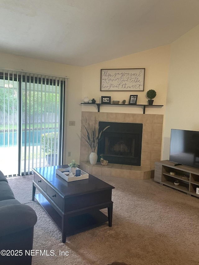 carpeted living room featuring a tiled fireplace