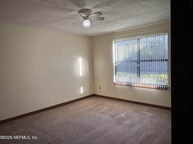 carpeted spare room featuring baseboards, a textured ceiling, and a ceiling fan