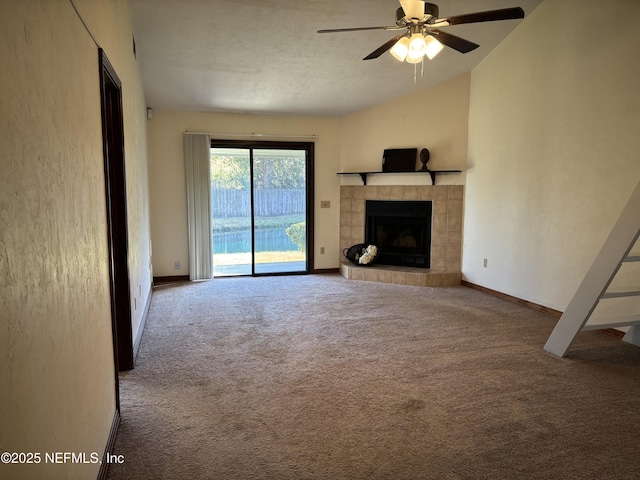 unfurnished living room featuring ceiling fan, baseboards, carpet, lofted ceiling, and a fireplace