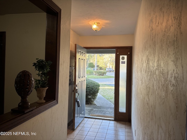 foyer entrance featuring light tile patterned floors and a textured wall