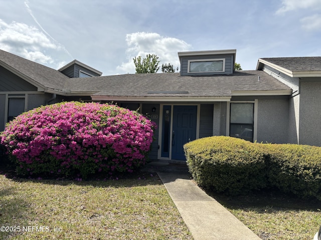 view of front of home featuring a front lawn, stucco siding, and roof with shingles