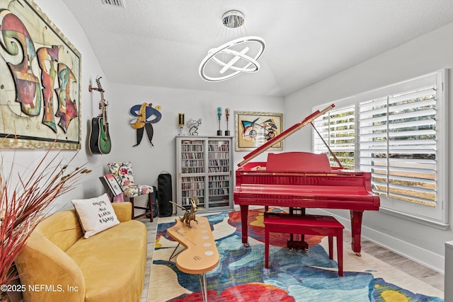 living area featuring a chandelier, lofted ceiling, and light hardwood / wood-style floors