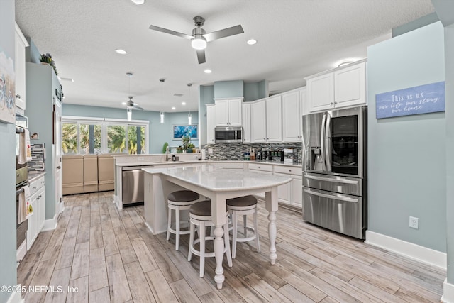 kitchen featuring appliances with stainless steel finishes, backsplash, white cabinetry, and a kitchen breakfast bar