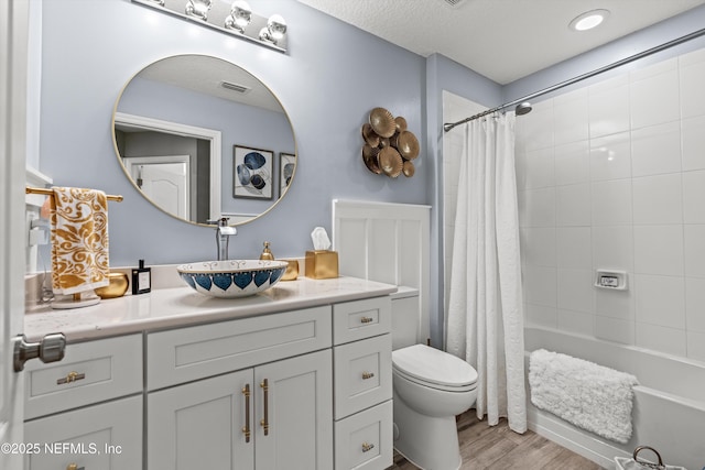 full bathroom with shower / bath combo, hardwood / wood-style floors, a textured ceiling, toilet, and vanity