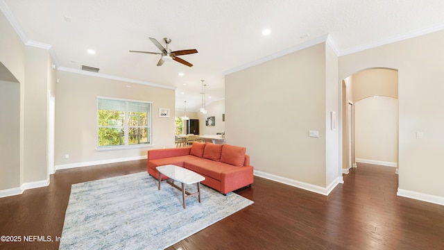 living room with crown molding, dark wood-type flooring, and ceiling fan