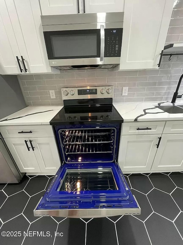 kitchen with white cabinets, decorative backsplash, and stainless steel appliances