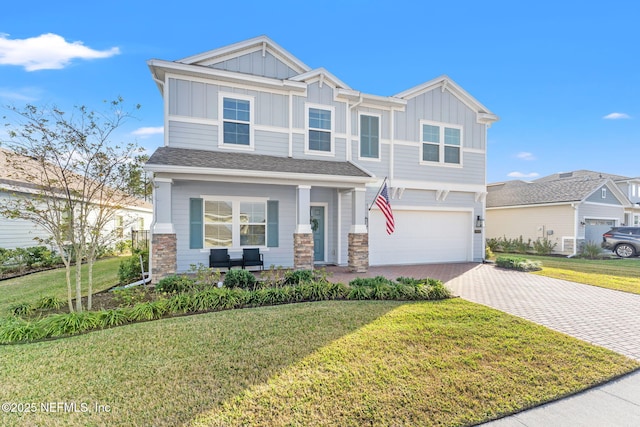 view of front of property featuring a front yard, a garage, and a porch