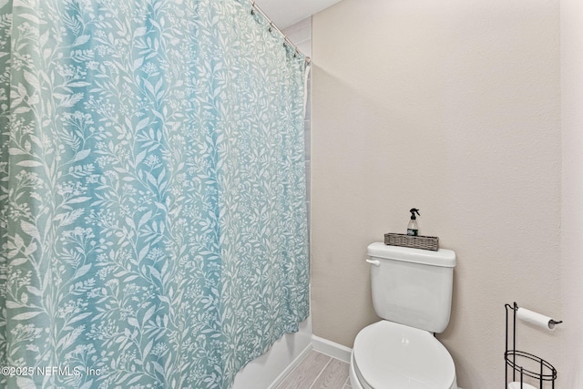 bathroom featuring toilet, hardwood / wood-style flooring, and shower / tub combo