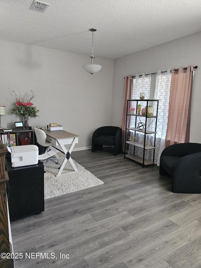 office area with visible vents, a textured ceiling, and wood finished floors