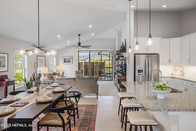 tiled dining area featuring ceiling fan, sink, and high vaulted ceiling