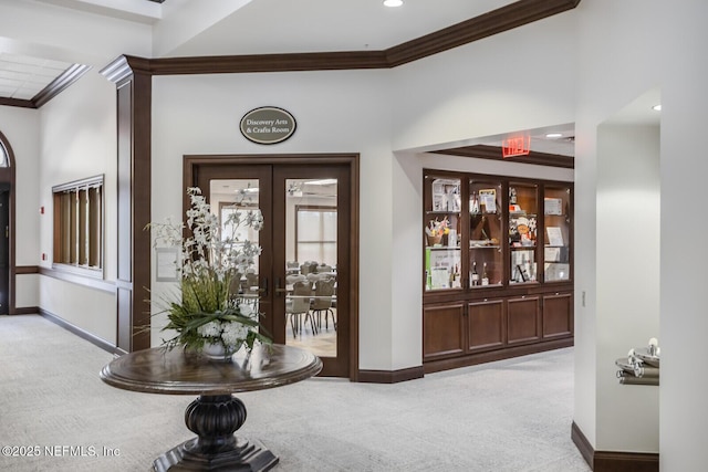 interior space featuring crown molding, french doors, and light colored carpet