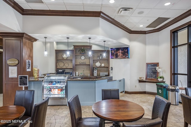 bar with dark brown cabinetry, a drop ceiling, hanging light fixtures, and ornamental molding